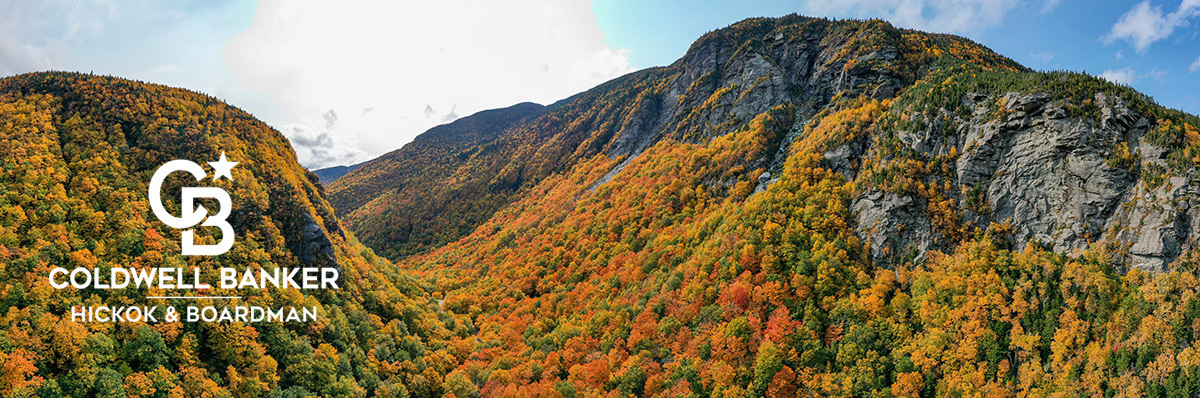 A mountain covered with colorful fall foliage with the CBHB logo superimposed in the left corner